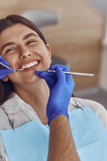 Professional doctor is checking woman's teeth in light modern dental clinic